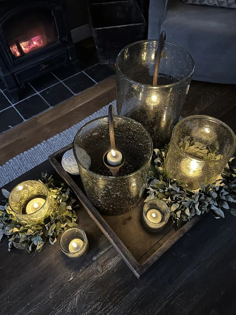 Landelijke sfeer met glazen waxinelichthouders en groen op houten dienblad bij My Sober Home
