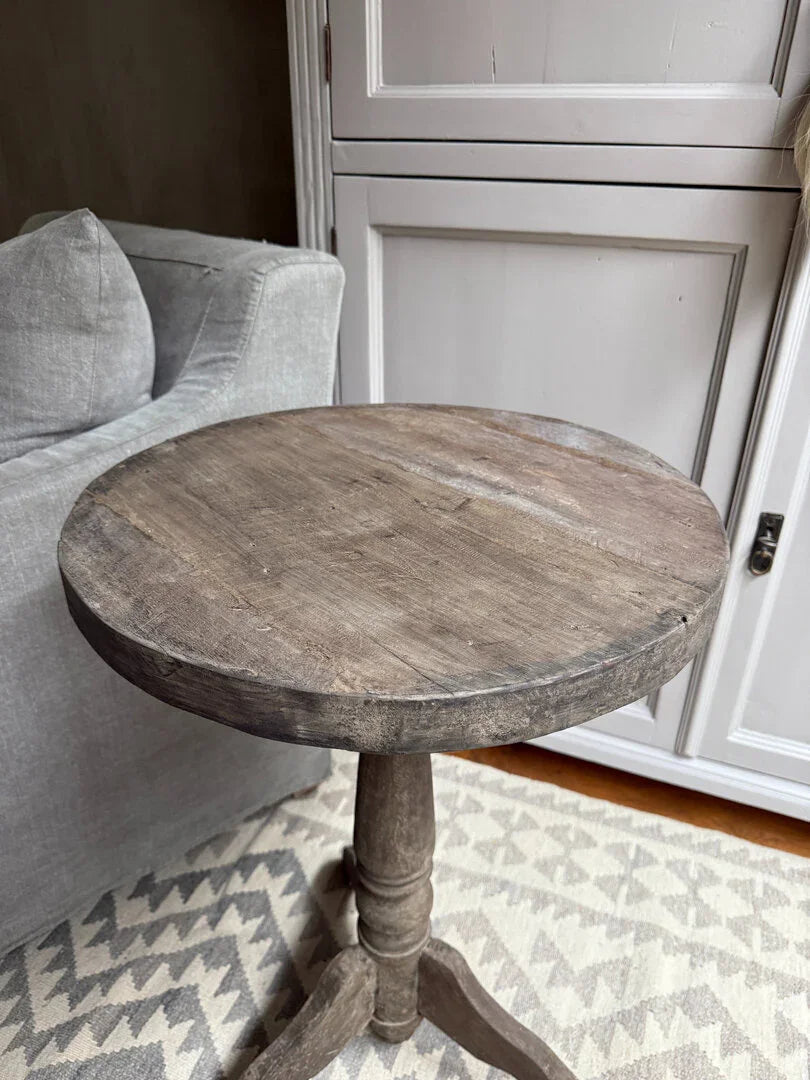 Authentieke ronde houten wijntafel op handgemaakt vloerkleed bij landelijke kast en bank