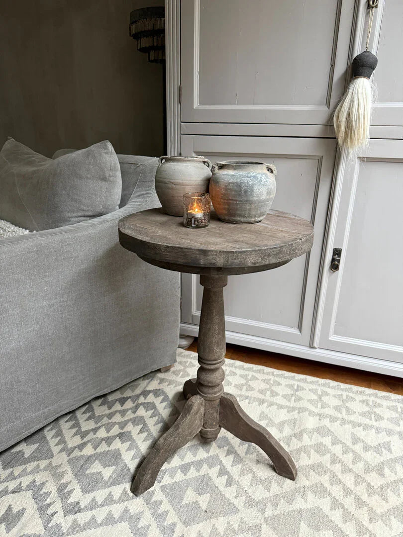 Houten wijntafel met twee aardewerken kruiken en waxinelichtje in sober, landelijk interieur