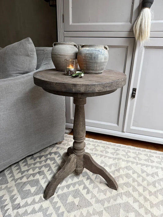 Oude houten wijntafel met twee grijze kruiken en kaarsje in landelijk sober interieur