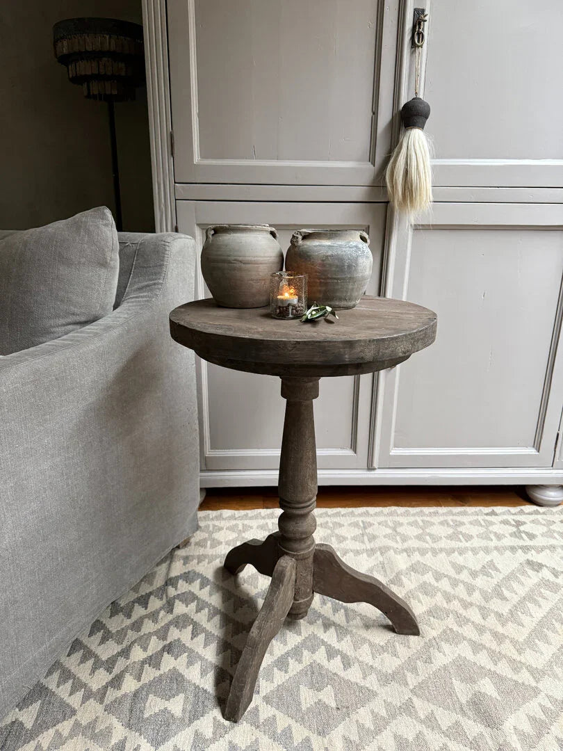 Handgemaakte houten wijntafel met aardewerken potten en kaars, sober landelijk interieur