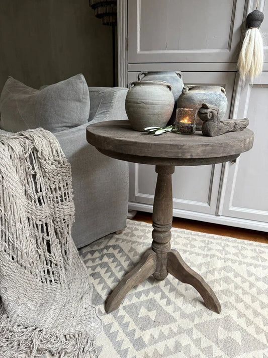 Houten wijntafeltje met keramieken potten en landelijke accessoires in sober interieur