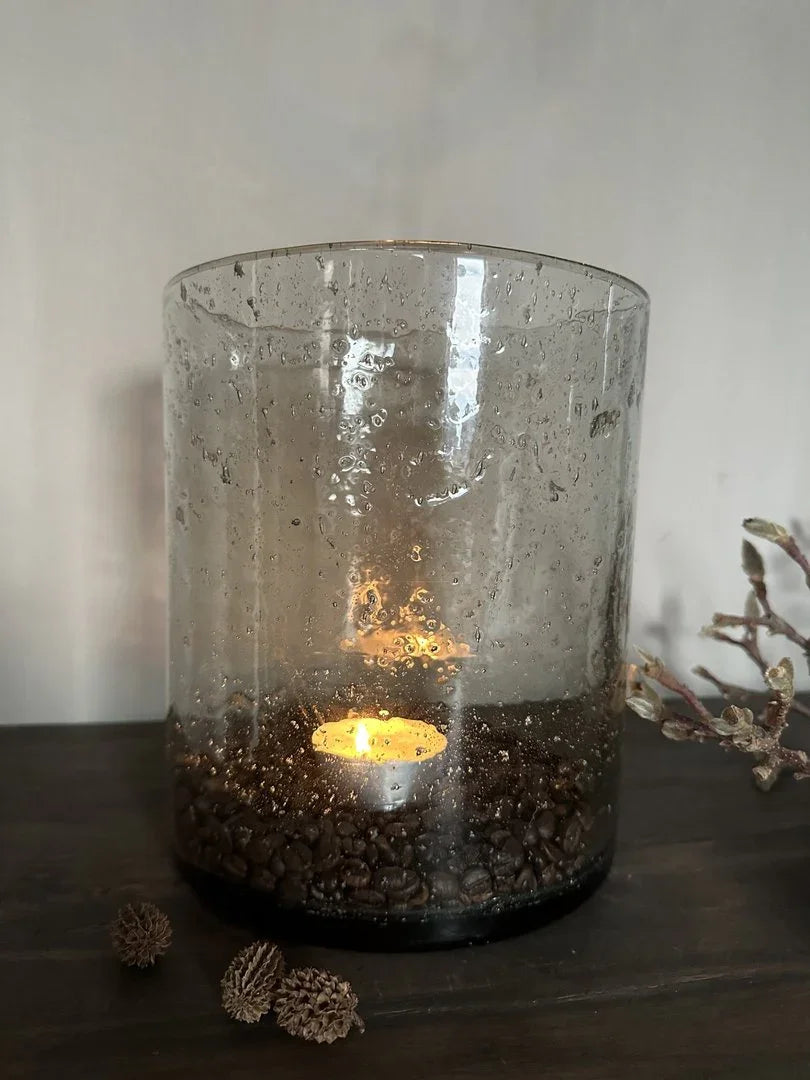 Windlicht van glas met steenslag, brandend waxinelichtje, sfeervol landelijk interieur