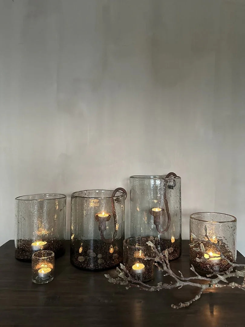 Sfeervolle handgemaakte windlichten met steenslag en kaarsen op donkere houten tafel, landelijk interieur