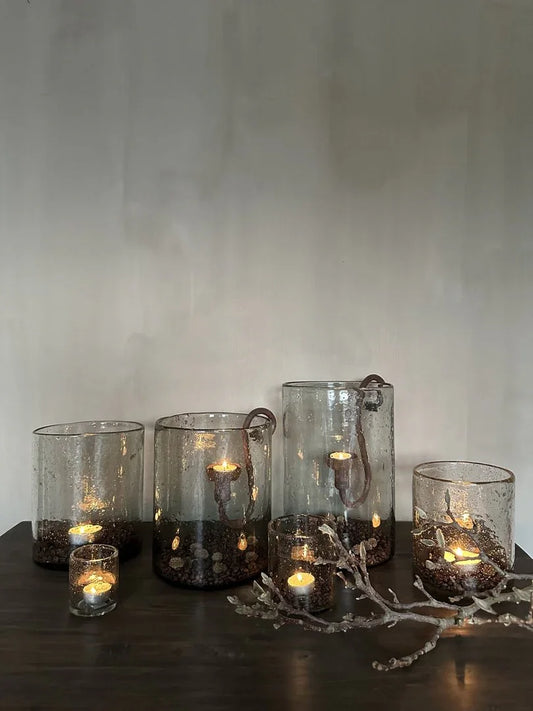 Sfeervolle handgemaakte windlichten met steenslag en kaarsen op donkere houten tafel, landelijk interieur