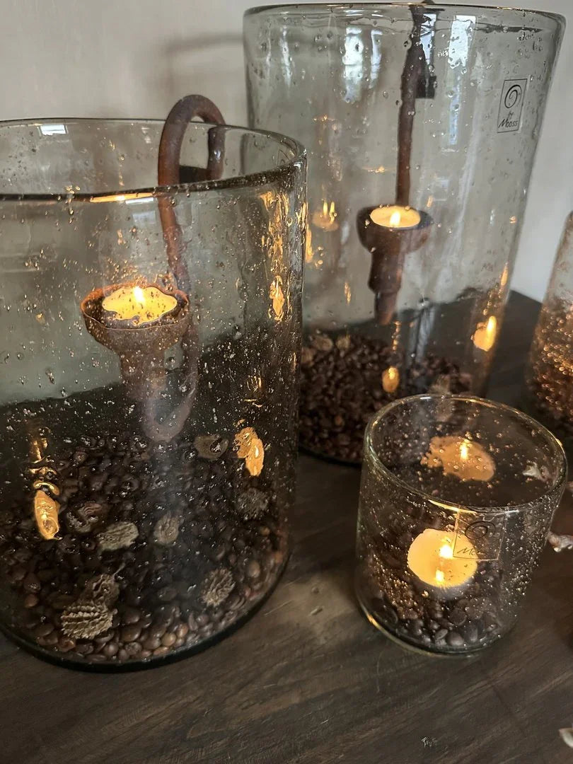 Handgemaakte glazen windlichten met kaarsen, steenslag en landelijke uitstraling op houten tafel