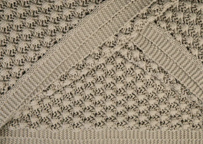 Close-up van beige woondeken met grof gehaakt patroon, landelijk en handgemaakt