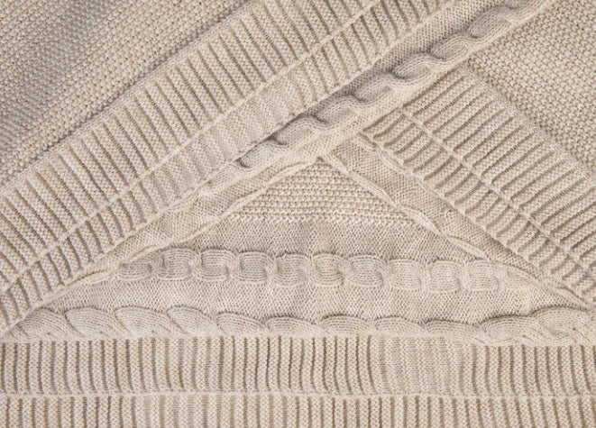 Close-up van beige gebreide woondeken met kabelpatroon, landelijk en sober interieuraccessoire.