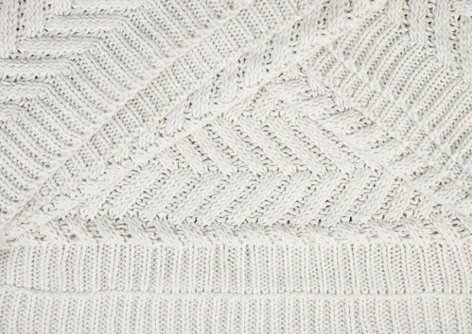 Close-up van handgebreide woondeken Vlieland Naturel met visgraatpatroon, sobere landelijke stijl