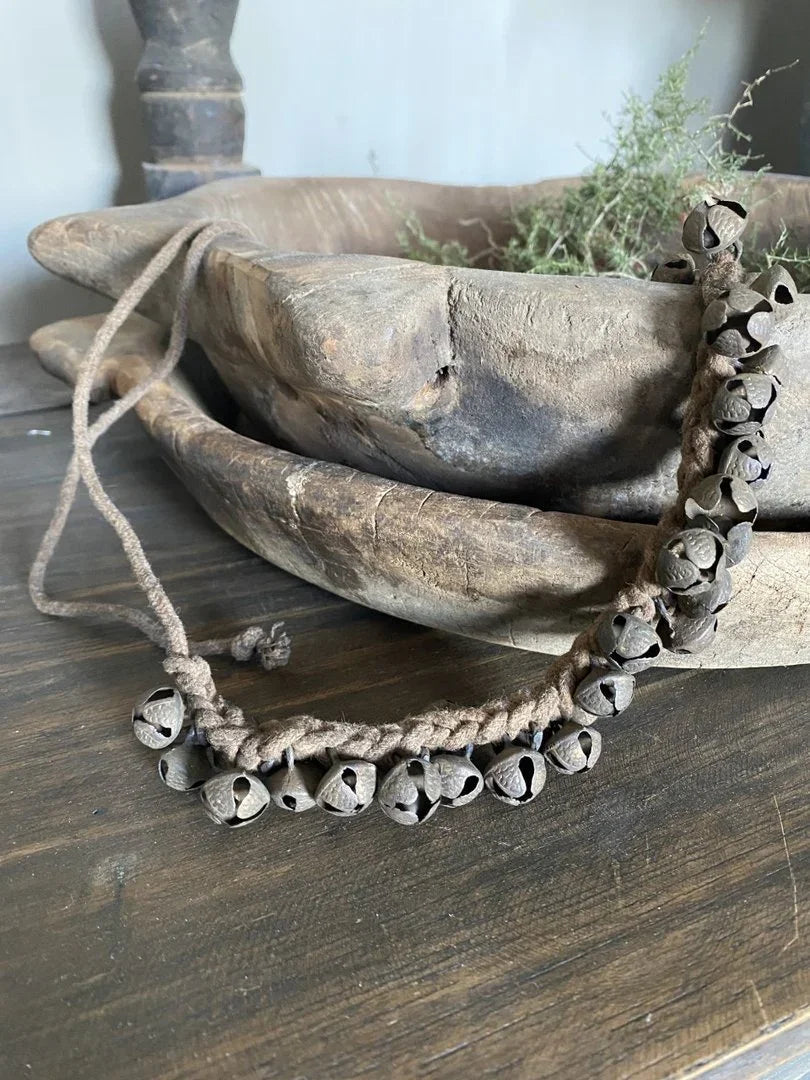 Handgemaakte landelijke belletjes aan touw op houten schaal, sober interieuraccessoire