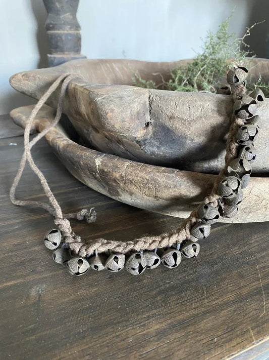 Handgemaakte landelijke belletjes aan touw op houten schaal, sober interieuraccessoire