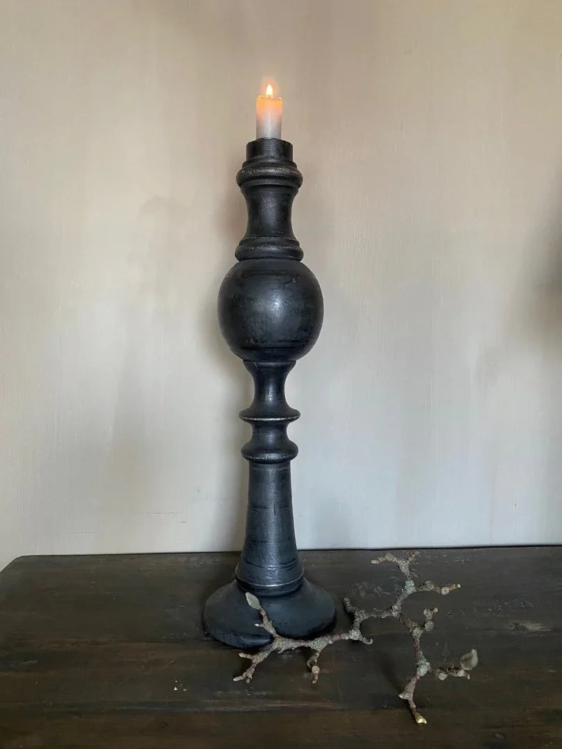 Zwarte houten kandelaar met brandende kaars, landelijk sober woonaccessoire op houten tafel