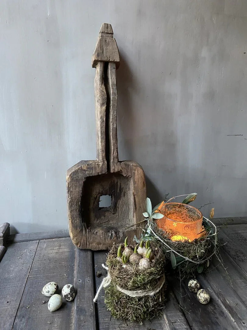 Authentiek houten ornament met mosdecoratie en kaars op donker houten tafel, landelijk interieur.